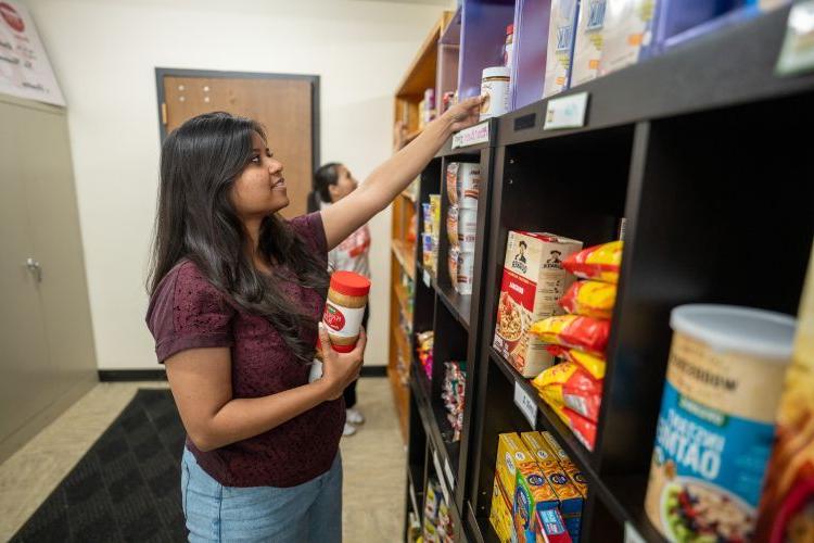 A student stocks shelves at the Pacific Food Pantry.